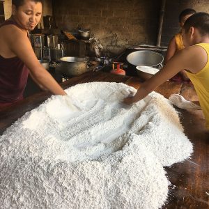 table with large pile of flour, with 2 boys working with it