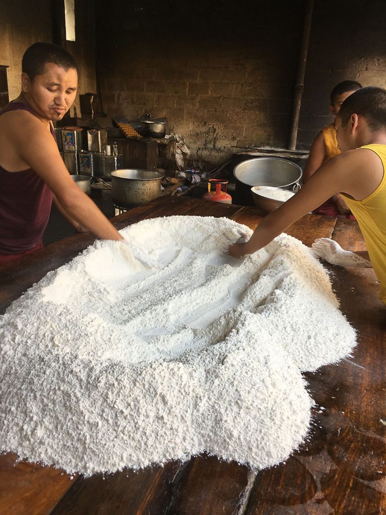 table with large pile of flour, with 2 boys working with it